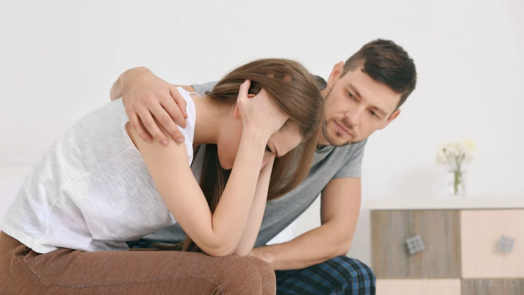 Un bărbat își consolează partenera tristă, care își ține capul în mâini